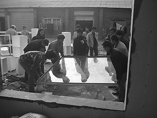 6──向かいの工場でペアガラスに ステンレスの枠をはめた後、職人総出で ガラスを開口部に設置する。ほぼ2m角。