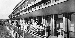 リチャード・デュッカー《ワイブリンゲンのサナトリウム》1928 近代建築は彼らの作品とその発表媒体にサナトリウムのイメージを付与した。白い壁、広いテラス、テラスに置かれたロング・チェア。近代人はそこで日光浴をし、結核を予防し、健康へと邁進する。彼らの都市はサナトリウム都市とも言える。しかしトーマス・マンが描いた『魔の山』（1924）の上のサナトリウム で、その規則的でゆっくりと流れる時間を生きていたのは、衛生的で明晰な近代人ではなく、あまりにも特徴的で混乱した個性の持ち主たちであった。