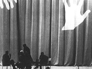3──コングレクスポのカーテン 引用出典＝O.M.A./Rem Koolhaas and Bruce Mau, S,M,L,XL, 010Publishers, 1995. コングレスのロビーとゼニス（コンサートホール）のステージ上部を繋ぐ扉にかかるカーテンは高さ6m幅31mもあり、手形があしらわれている。テレビ取材に応えるコールハースの手がこれに呼応するところを捉えた写真。